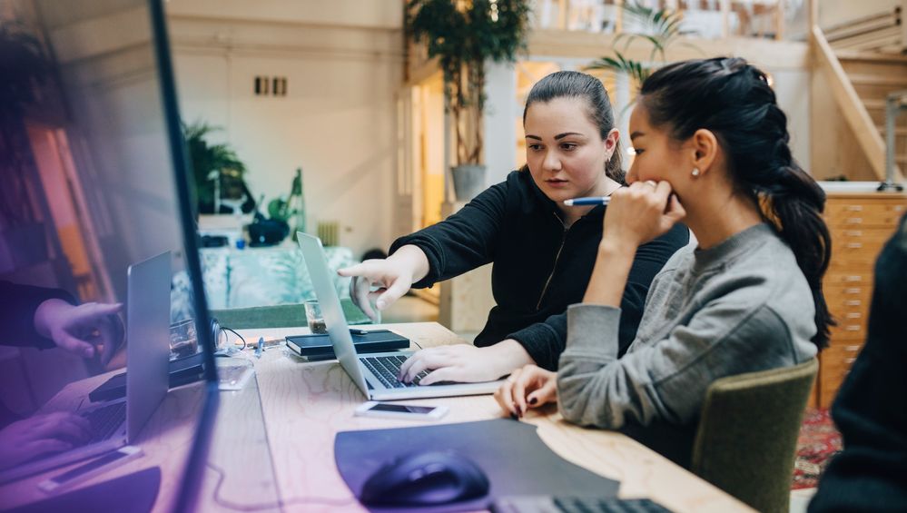 female-coworkers-discussing-coding-on-laptop-while-sitting-in-office-1138450906-hero-medium[1].jpg